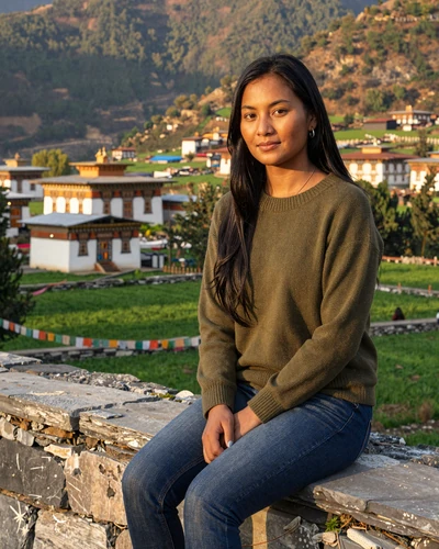 Bhutanese woman relaxing in a scenic Himalayan valley with traditional houses and prayer flags - authentic Bhutanese singles on DatingSites2