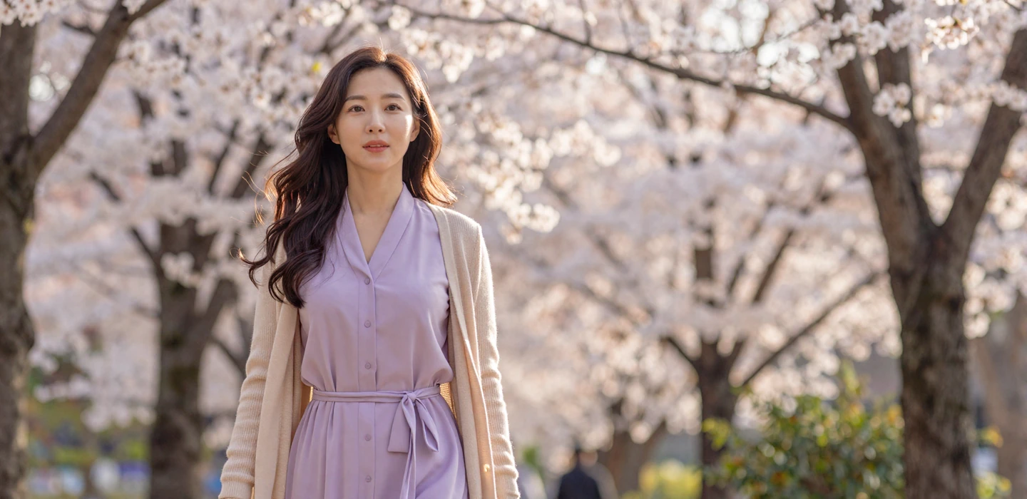 Beautiful Korean heritage woman walking through cherry blossom park in soft spring sunlight - North Korean women dating on DatingSites2