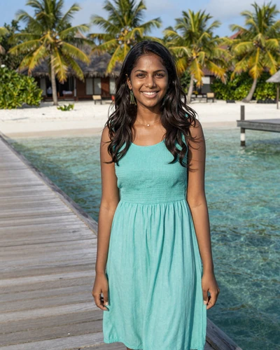 Maldivian woman in turquoise dress on a traditional jetty over crystal-clear island waters - Maldivian dating culture